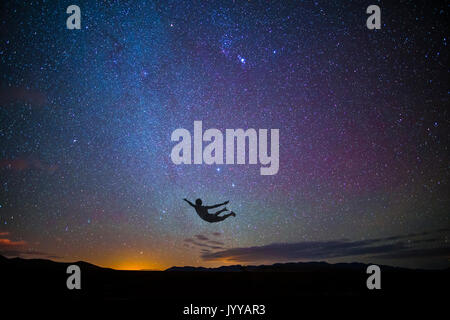 Ragazzo salti in aria al tramonto con le stelle Foto Stock