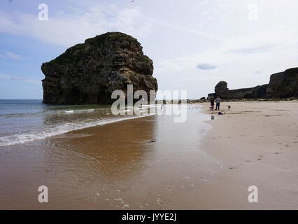 La gente sulla spiaggia a Marsden Rock una formazione rocciosa di calcare fuori del litorale del Mare del Nord a South Shields Inghilterra Foto Stock