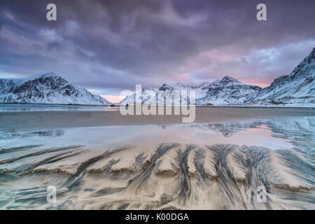 Onde il surreale Skagsanden spiaggia circondata da montagne coperte di neve. Isole Lofoten in Norvegia. Europa Foto Stock