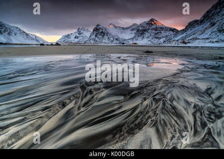 Onde il surreale Skagsanden spiaggia circondata da montagne coperte di neve. Isole Lofoten in Norvegia. Europa Foto Stock