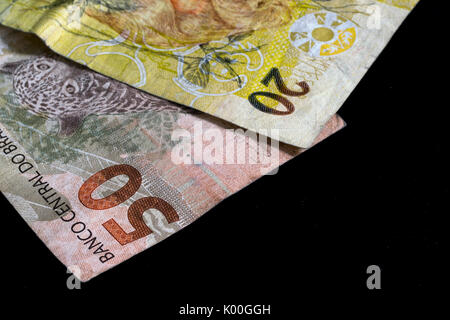 Due brasiliane denaro reale note,di 50 e 20 Valore, moneta del Brasile, su uno sfondo nero, closeup macro Foto Stock