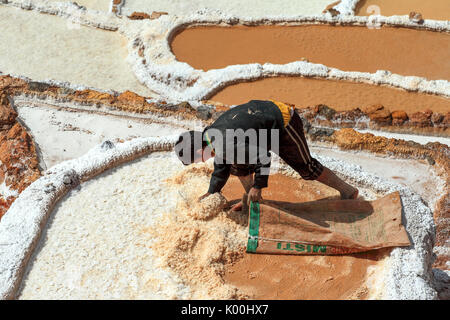 Un giovane uomo lavora la raccolta del sale nelle saline di Maras Cusco Peru Sud America Foto Stock