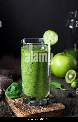 Frullato di verde in vetro. Pulizia sano detox drink per lo sport e lo yoga, uno stile di vita sano. Verticale, primo piano e sfondo nero Foto Stock