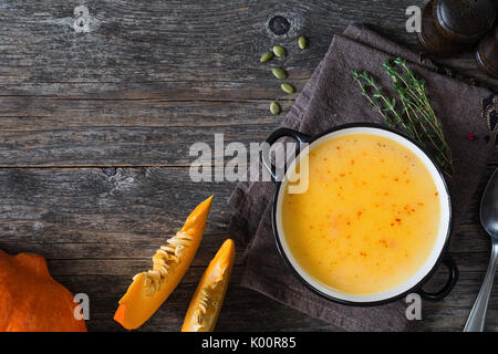 Ciotola di crema di zucca zuppa su tovagliolo sulla tavola in legno rustico sfondo. Vista superiore e copiare lo spazio per testo Foto Stock