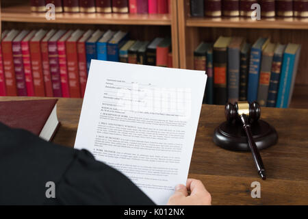 Elevato angolo di visione dei maschi di giudicare la lettura di documenti legali al banco nelle aule di tribunale Foto Stock