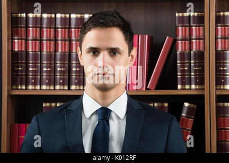 Ritratto di fiducia avvocato maschio contro scaffale in aula Foto Stock