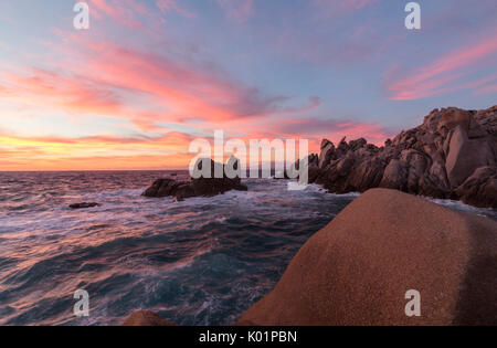 Cielo rosa al tramonto sulle onde che si infrangono sulle scogliere di Capo Testa a Santa Teresa di Gallura in provincia di Sassari Sardegna Italia Europa Foto Stock