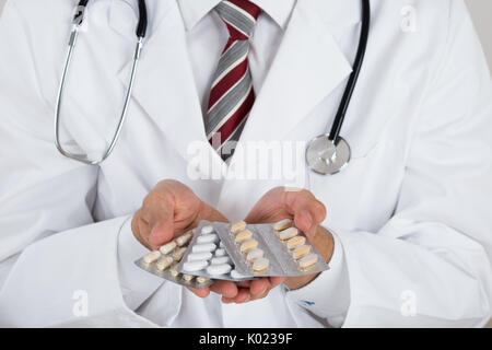 Sezione mediana del medico tenendo blister contro uno sfondo bianco Foto Stock