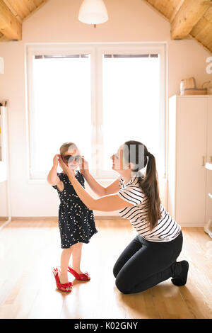 Mamma mette su occhiali da sole per il suo incantevole piccola figlia. Foto Stock