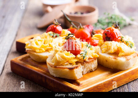 Bruschetta con uova strapazzate e cotta a forno e pomodori ciliegini, delizioso antipasto estivo Foto Stock