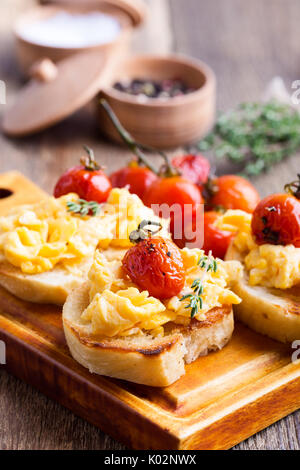 Bruschetta con uova strapazzate e cotta a forno e pomodori ciliegini, delizioso antipasto estivo Foto Stock