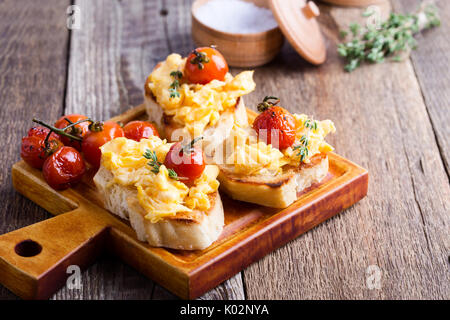 Bruschetta con uova strapazzate e cotta a forno e pomodori ciliegini, delizioso antipasto estivo Foto Stock