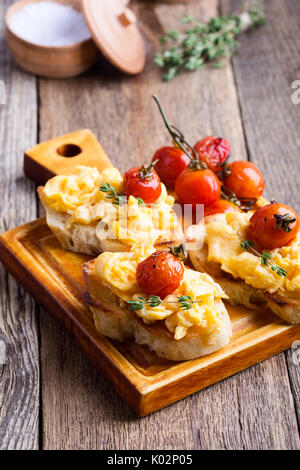 Bruschetta con uova strapazzate e cotta a forno e pomodori ciliegini, delizioso antipasto estivo Foto Stock