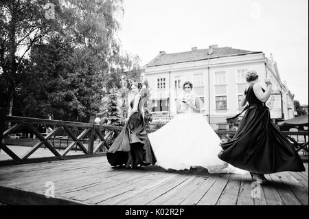 Sposa favolose passeggiate, posa e divertirsi con le sue damigelle nel centro cittadino in un giorno di nozze. Foto in bianco e nero. Foto Stock