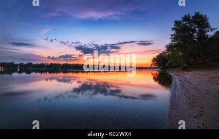Tranquillo paesaggio con fiume e colorato il cielo con le nuvole al tramonto. Un paesaggio fantastico con il lago, blu cielo con l'arancione e il rosso nuvole riflettono in acqua Foto Stock