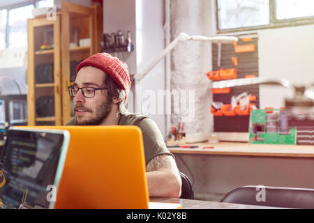 Maschio di designer che lavora al computer portatile in officina Foto Stock