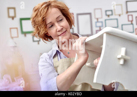 Femmina matura artigiano facendo panca in legno in arte studio Foto Stock