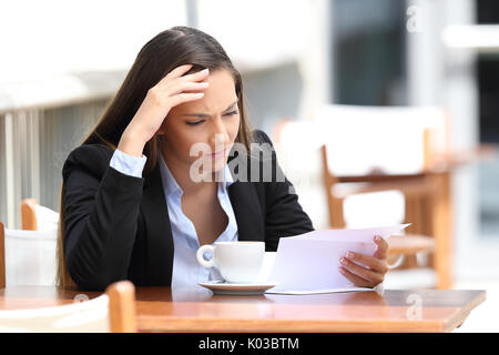 Preoccupato executive la lettura di una lettera seduti in un caffè Foto Stock