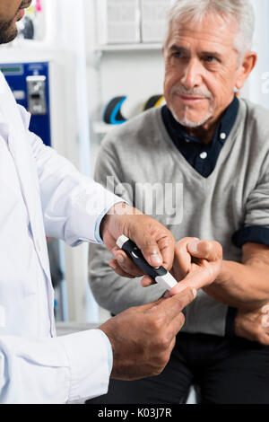 Il controllo medico del paziente Senior del livello di zucchero con il glucometro Foto Stock