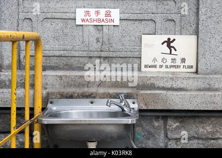 Dissipatore di acciaio appendere al muro di pietra sulla strada nel centro citta'. Il vuoto di un bagno pubblico in Hong Kong. Foto Stock