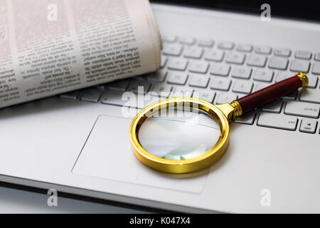 Informazioni sul concetto di ricerca. giornale e lente di ingrandimento sulla tastiera Foto Stock