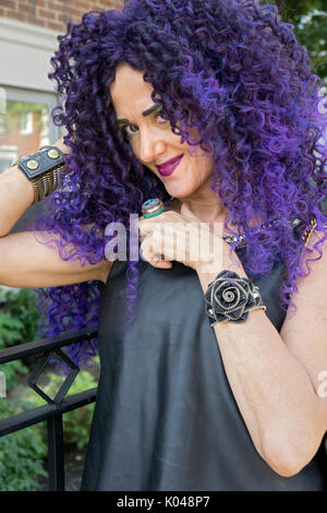 Un quasi cinquanta anni cerca donna giovane con lunghi viola i capelli ricci e un vestito estivo nel Greenwich Village di New York City. Foto Stock