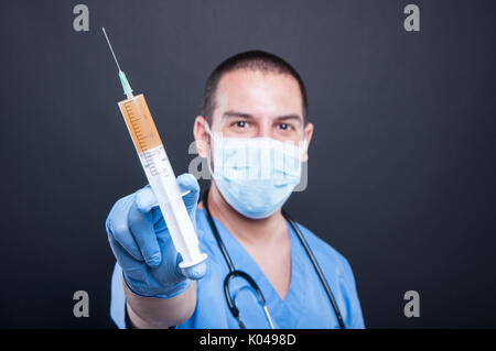 Messa a fuoco selettiva di medic indossando scrubs illustrante la siringa su sfondo nero Foto Stock