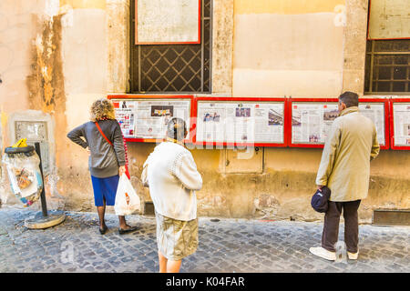 Persone che leggono l'unita quotidiano sul display al di fuori della locale sezione pci nel centro storico della città di Roma Foto Stock