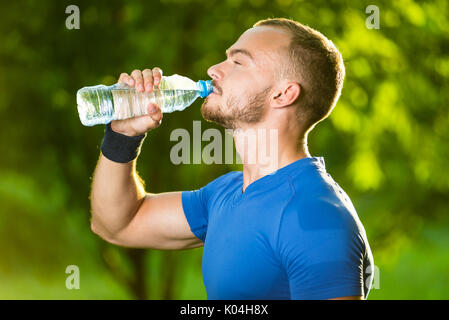 Athletic uomo maturo di bere acqua da una bottiglia Foto Stock