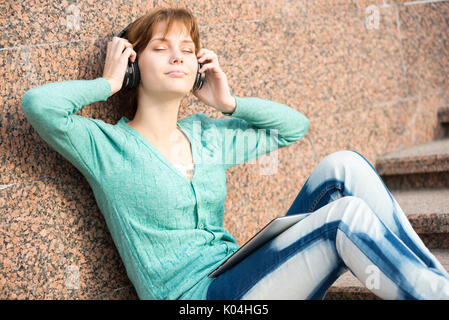 Bella donna giovane studente con le cuffie. Musica all'aperto ragazza Foto Stock