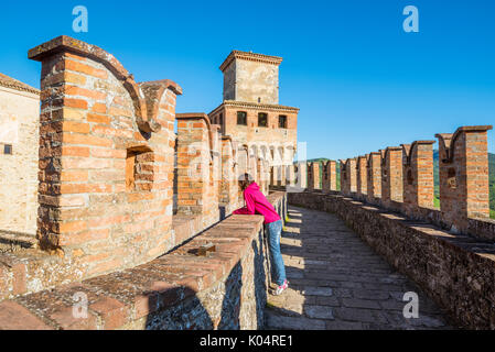 Vigoleno, Piacenza, Emiglia-Romagna, Italia. Donna in piedi sulle mura del castello cercando la città sottostante. Foto Stock