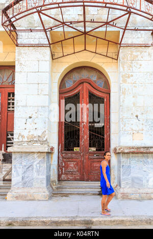 Donna cammina davanti ad un architettura art deco ingresso nella Habana Vieja, Havana, Cuba Foto Stock