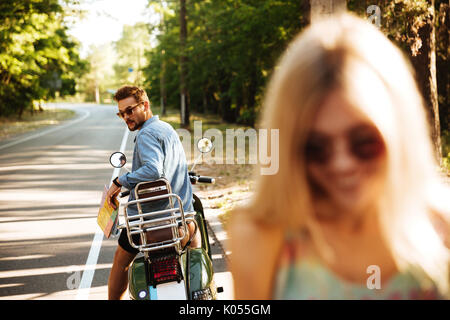 Foto di giovani felici amare giovane vicino a scooter all'esterno. Guardando a parte. Focus sull'uomo. Foto Stock