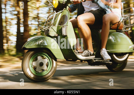 Immagine ritagliata del giovane uomo barbuto su uno scooter con la fidanzata all'esterno. Foto Stock