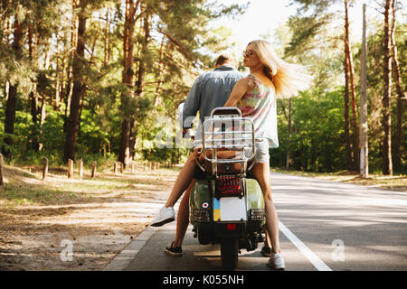 Vista posteriore immagine del giovane uomo su scooter con la fidanzata all'esterno. Foto Stock