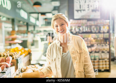Ritratto sorridente giovane donna a fare la spesa nel mercato Foto Stock