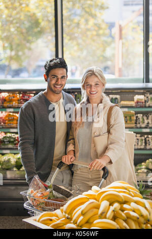 Ritratto sorridente coppia giovane a fare la spesa nel mercato Foto Stock