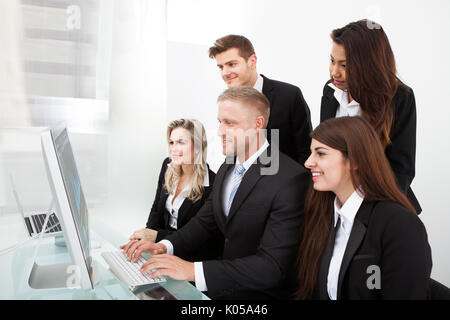 Gruppo di imprenditori utilizzando PC desktop insieme in ufficio Foto Stock