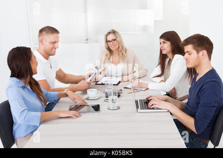 Ritratto di bella imprenditrice nell incontro con i colleghi in ufficio Foto Stock