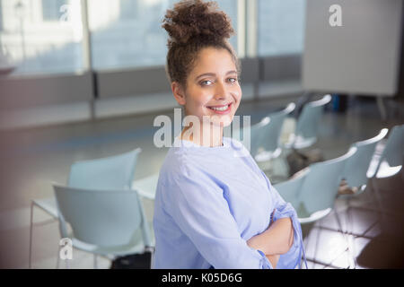 Ritratto sorridente, fiducioso giovane imprenditrice in sala conferenze Foto Stock