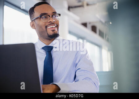 Sorridente imprenditore lavora al computer portatile in ufficio Foto Stock
