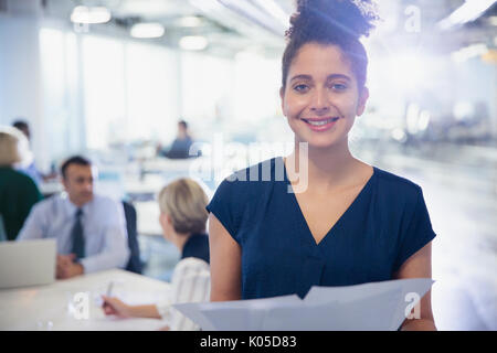 Ritratto sorridente, fiducioso giovane imprenditrice con i documenti di office Foto Stock