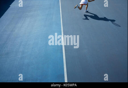 Ombra del tennis femminile player in esecuzione su blu soleggiato Campo da tennis Foto Stock