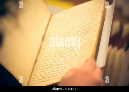 Un sopra la spalla colpo di uno studente di college mantenere aperto un antico libro, 2016. Foto Stock