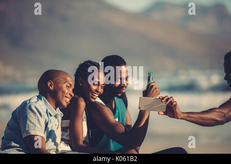 Gruppo di happy amici divertendosi insieme e tenendo selfie utilizzando il telefono cellulare. Ritratto Di Auto al party in spiaggia. Foto Stock