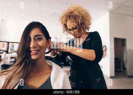 Donna parrucchiere a lavorare in salone. Giovane donna ottenendo un elegante taglio di capelli fatto a salon. Foto Stock