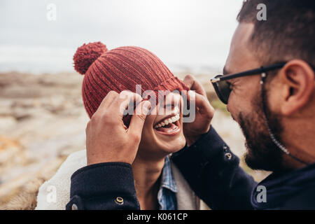 Amare giovane avendo divertimento all'aperto. Uomo che copre gli occhi di donna con cappello. Foto Stock