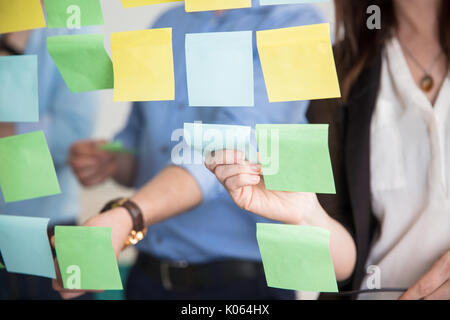 Sezione mediana della gente di affari di incollaggio note di adesivo sul vetro Foto Stock