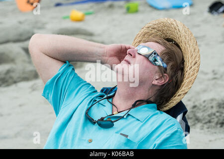 Charleston, Isle of Palms, STATI UNITI D'AMERICA. 21 Ago, 2017. Un uomo si rilassa in una spiaggia sedia come ella visualizza l'eclisse solare totale sulla spiaggia al di fuori di Charleston Agosto 21, 2017 a Isle of Palms, Carolina del Sud. L'eclissi solare dopo ampie in tutta la nazione attraversa la zona di Charleston, prima di dirigervi sopra l'Oceano Atlantico. Credito: Planetpix/Alamy Live News Foto Stock