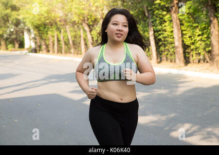 Donna grassa in esecuzione esercizio faccia sorridere nel parco la perdita di peso di concetto Foto Stock